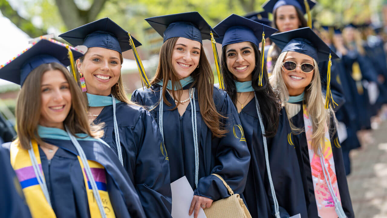 Graduates gather in for a photo, smiling brightly in anticipation for the Commencement ceremony ahead.