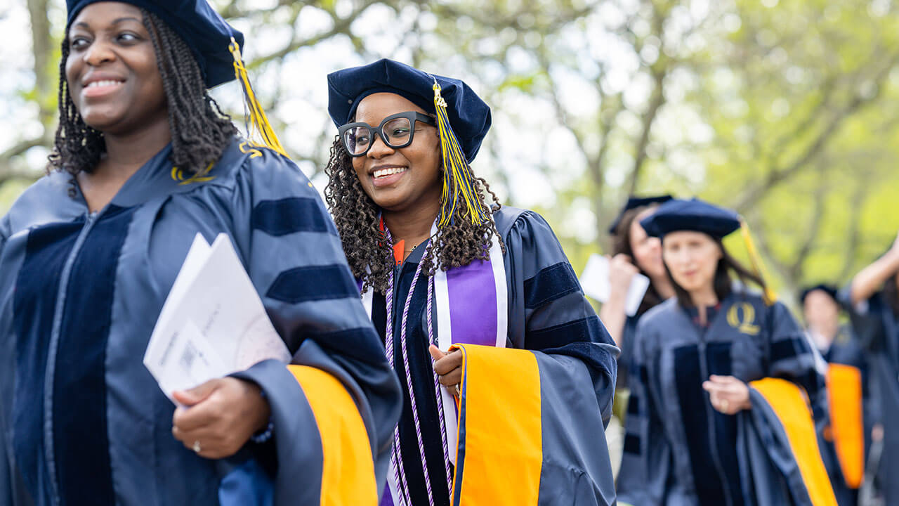 graduates smile while processing in