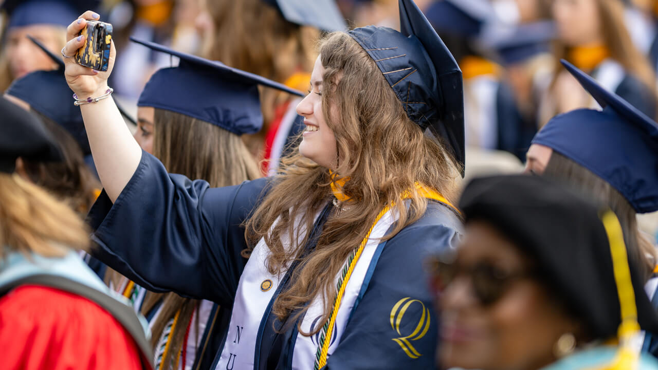 A graduate takes a photo with her cell phone