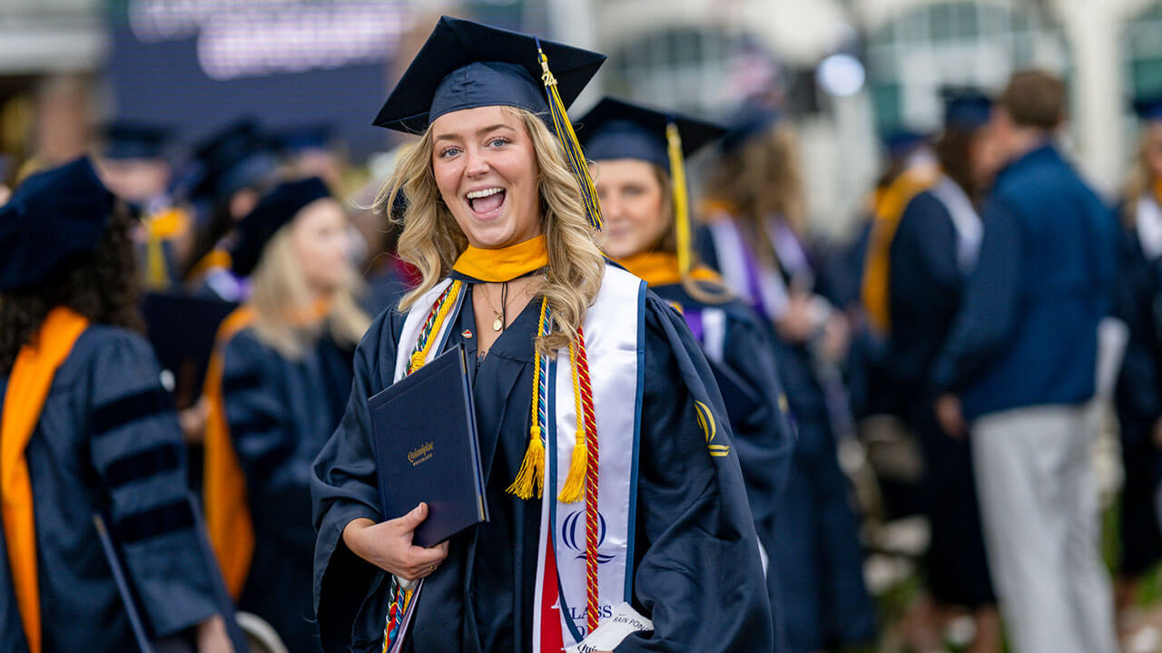 graduate poses with diploma smiling widely