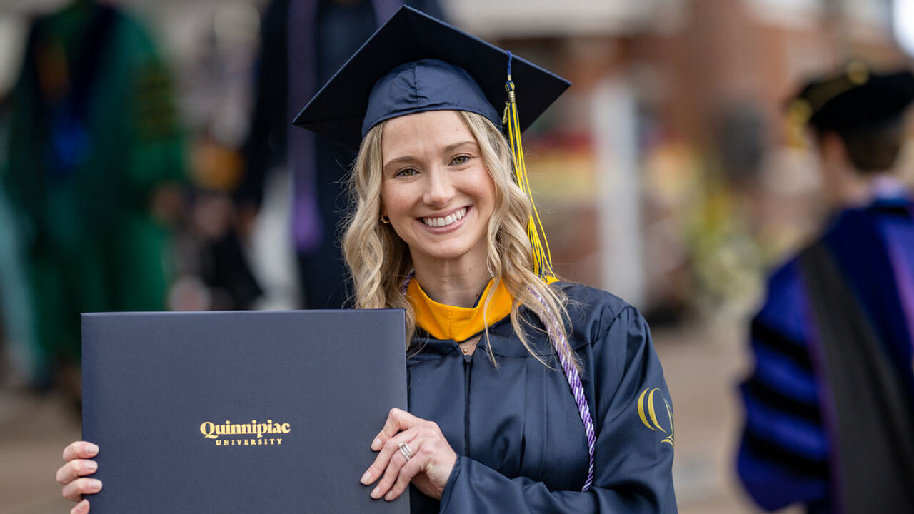 Proudly, a graduate student holds up their degree after the ceremony.