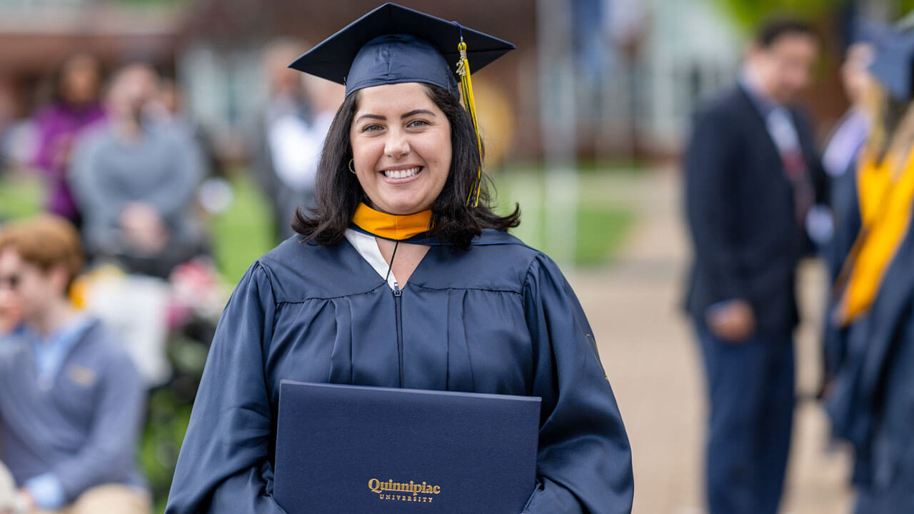 In celebration, a 2024 graduate holds up their diploma happily.