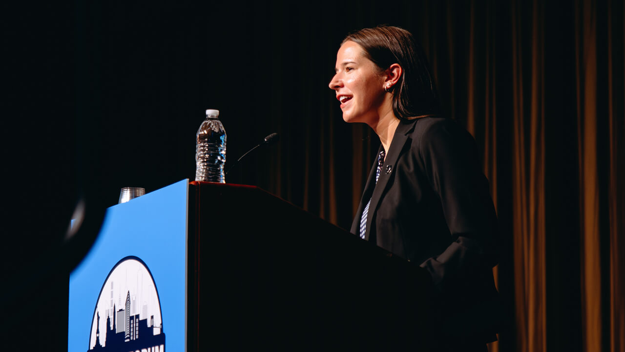 Quinnipiac professor speaks at a podium on stage at GAME Forum