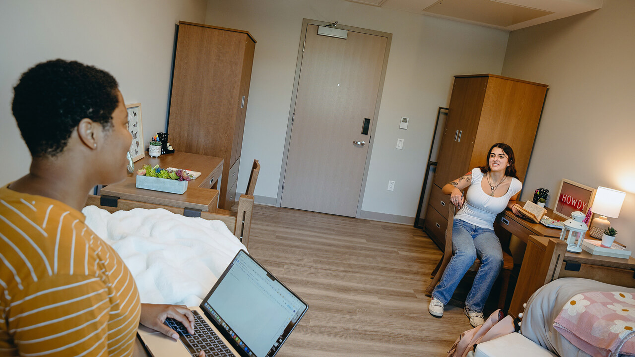 Two students talk in dorm room