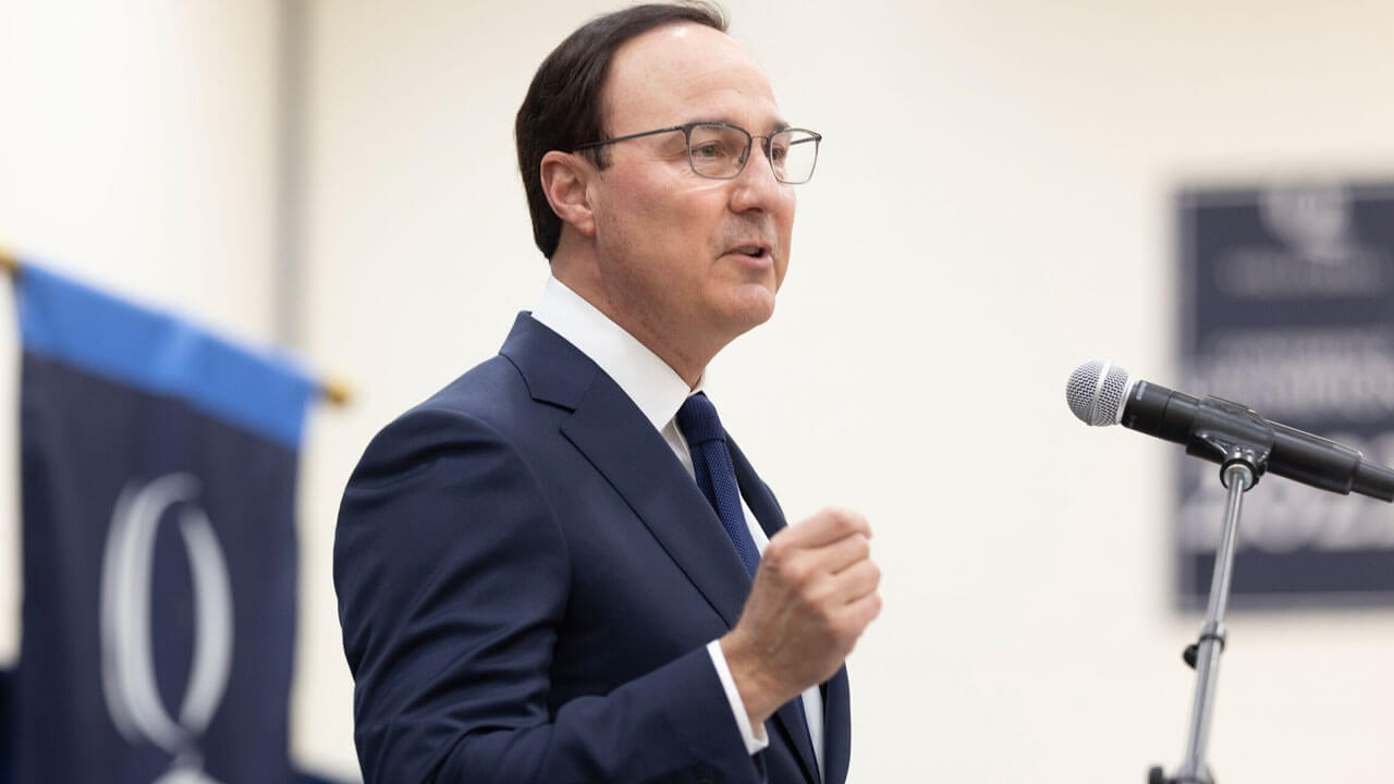 Dean Phil Boiselle speaks into a microphone on stage during Match Day