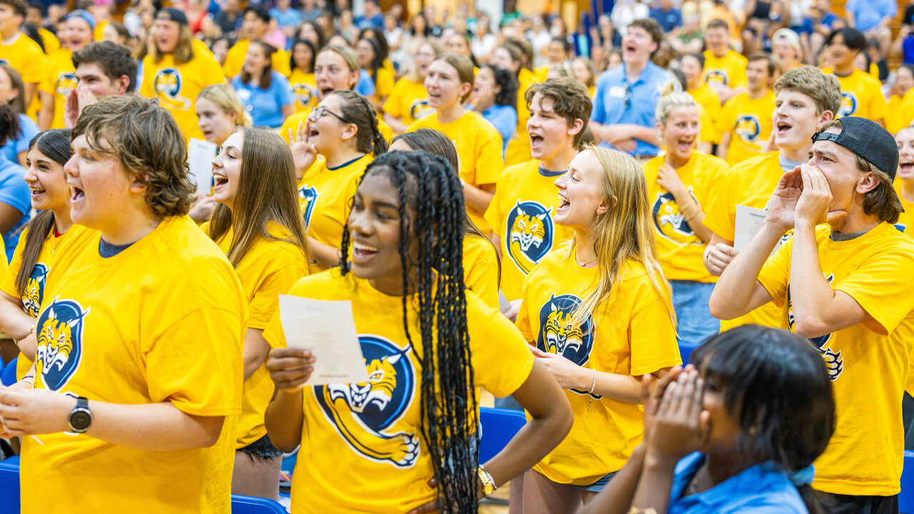 Students wear yellow shirts and read off a sheet of paper