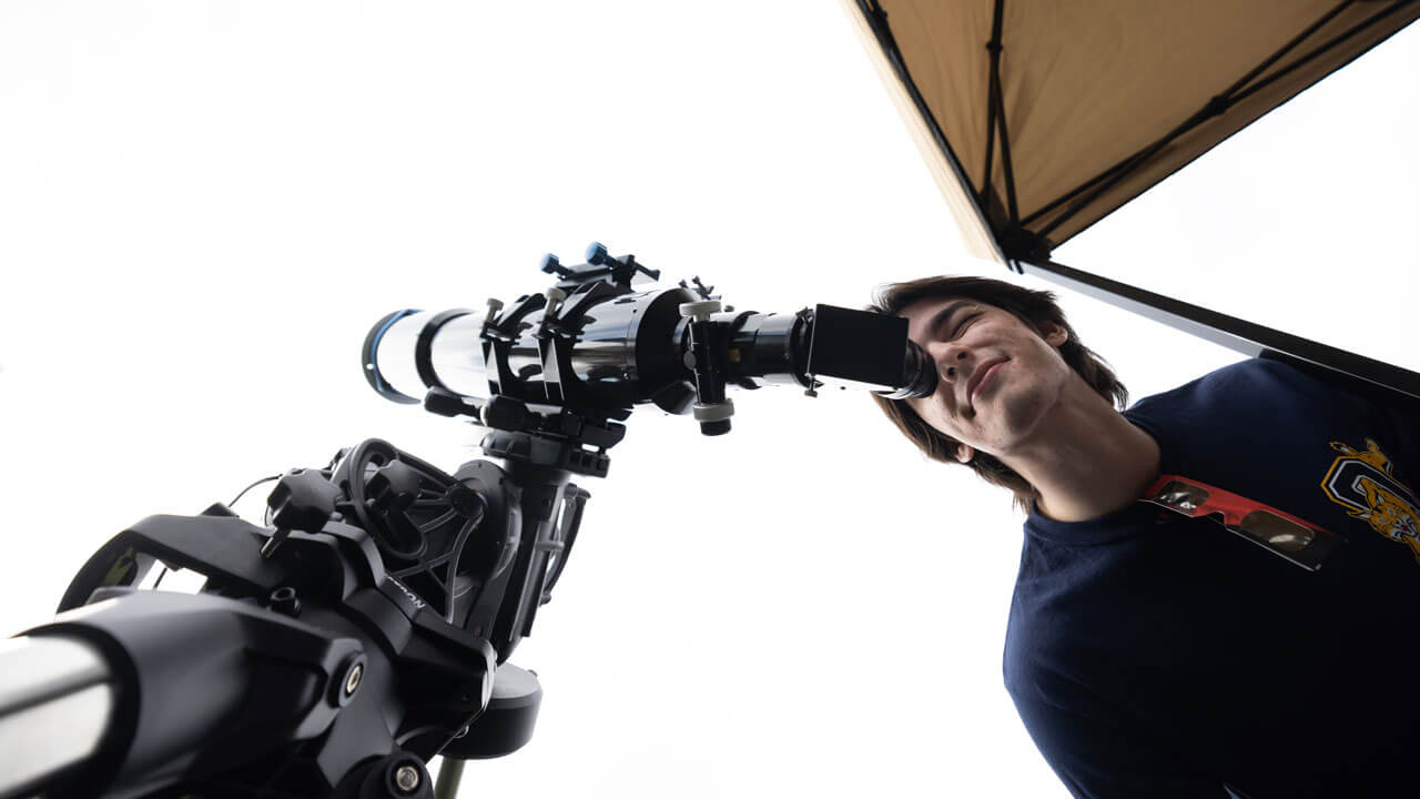 A student looks through a telescope.