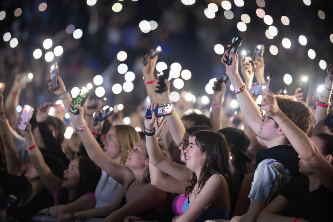 Students in the crowd below the stage cheer for Flo Rida performance and wave their flashlights