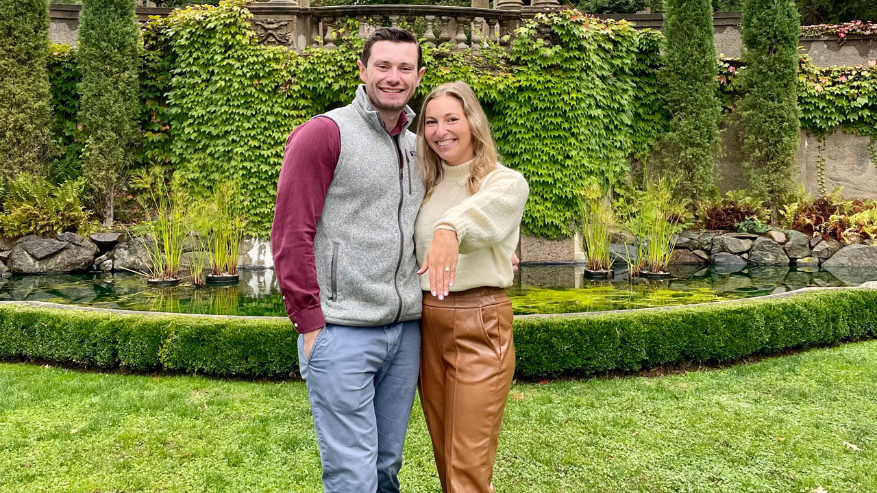 Samantha Eisenberg and Anthony Sullivan smiling as Samantha holds out her hand with an engagement ring on.