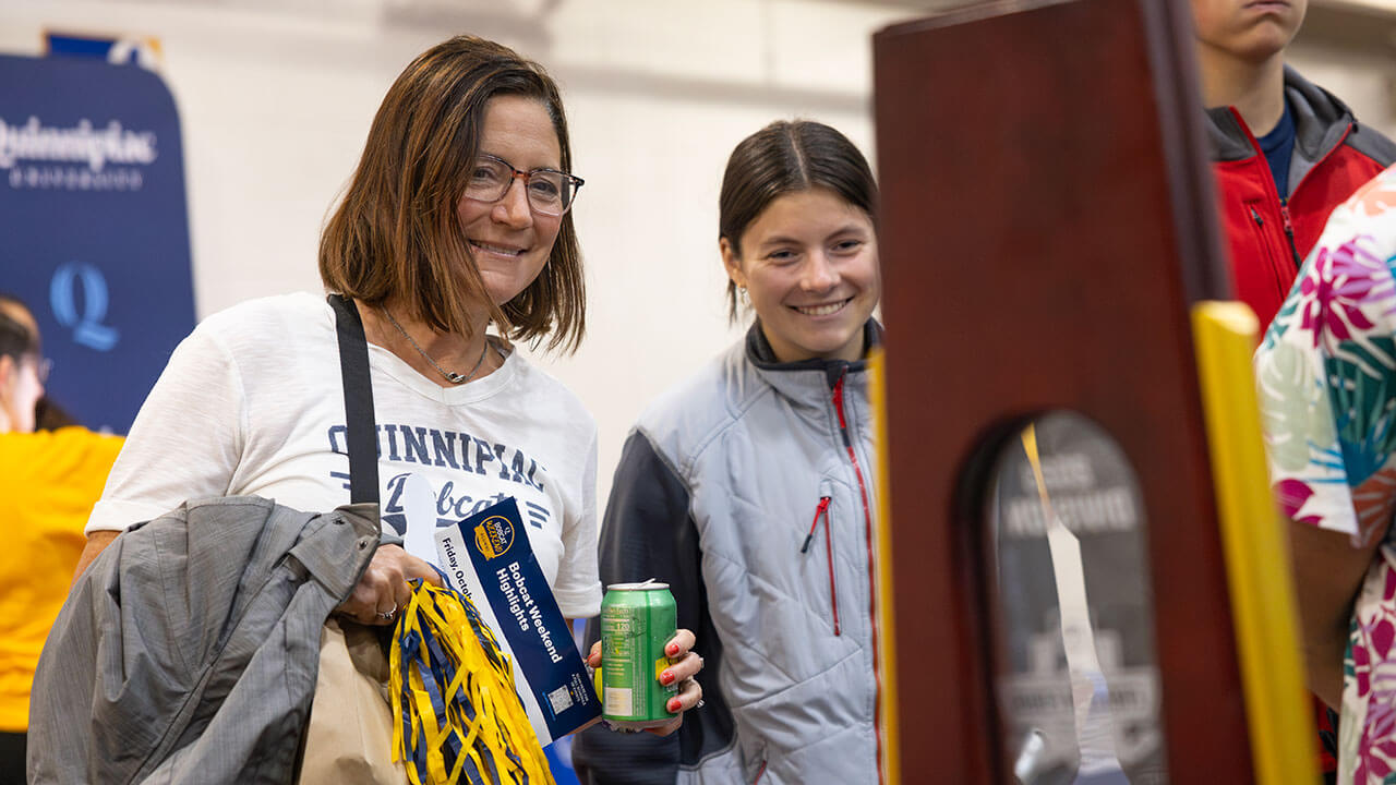 A student and her family smiles as they look at the NCAA National Championship trophy