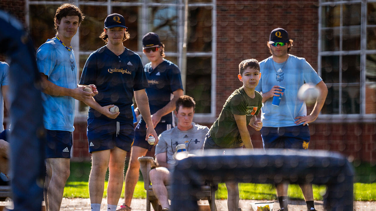 Quinnipiac mens baseball team playing baseball with event goers