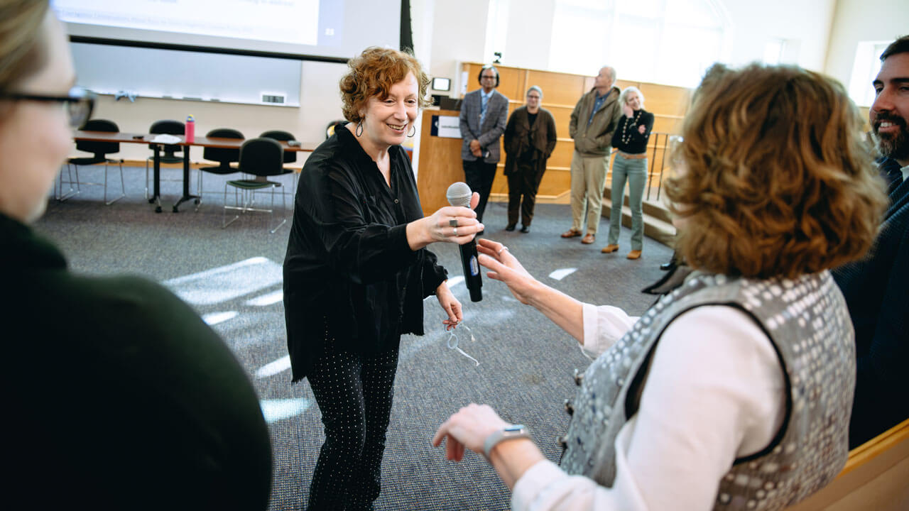 A presenter hands a microphone to an attendee.