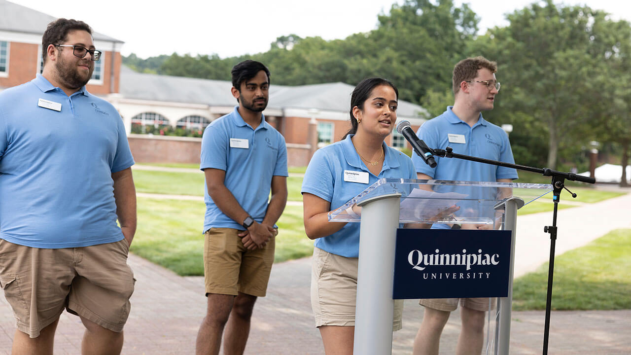 Orientation leaders speak from a podium on the quad