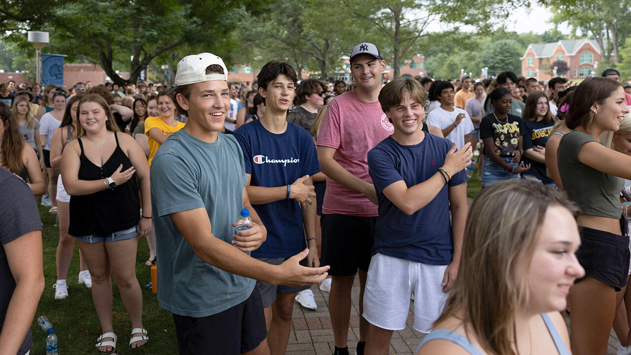 Hundreds of students do the Quinnipiac Bobcat swipe arm motion