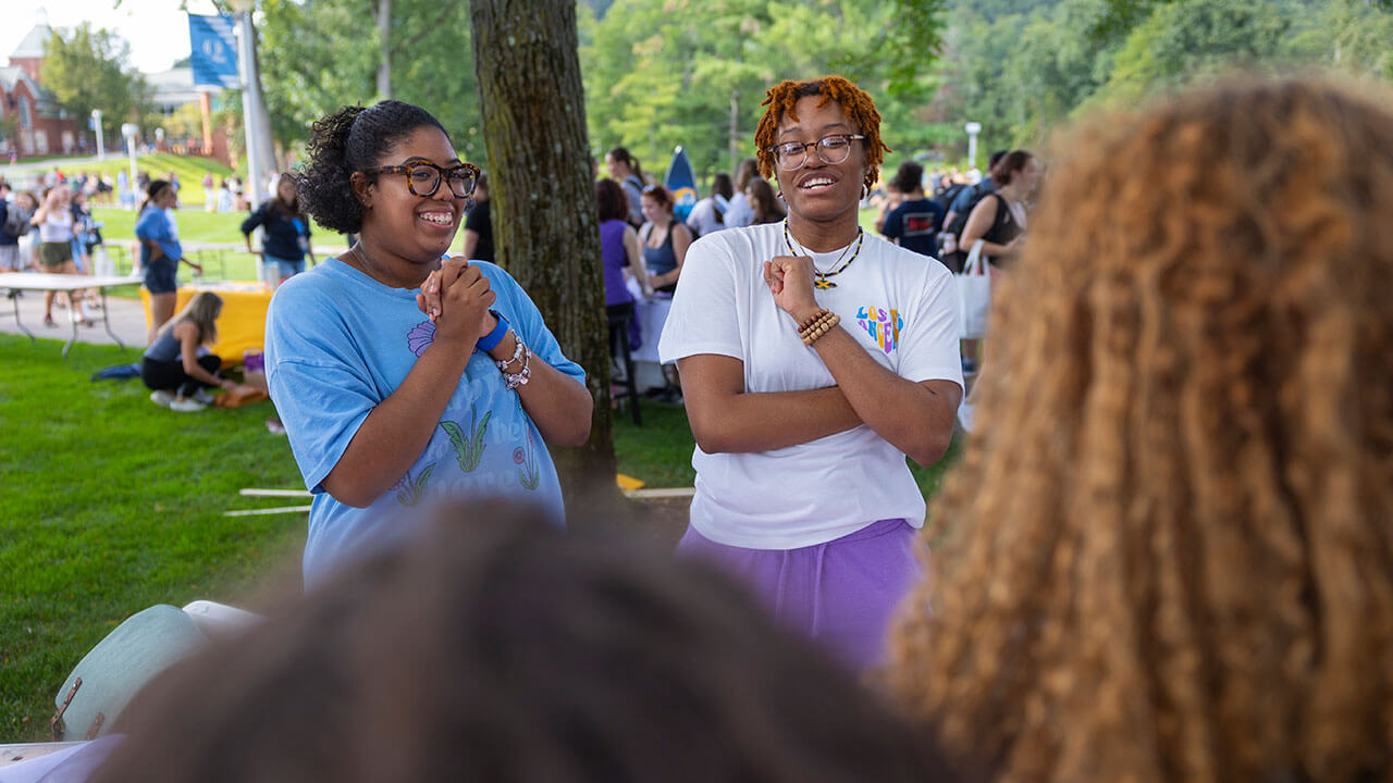 Students smile as they talk with other Quinnipiac students