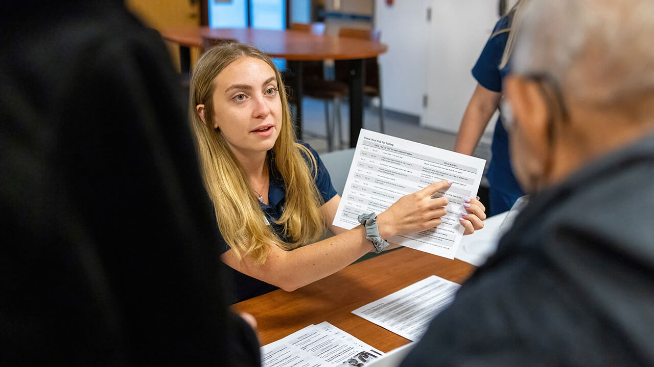 A student explains a fact sheet about fall prevention