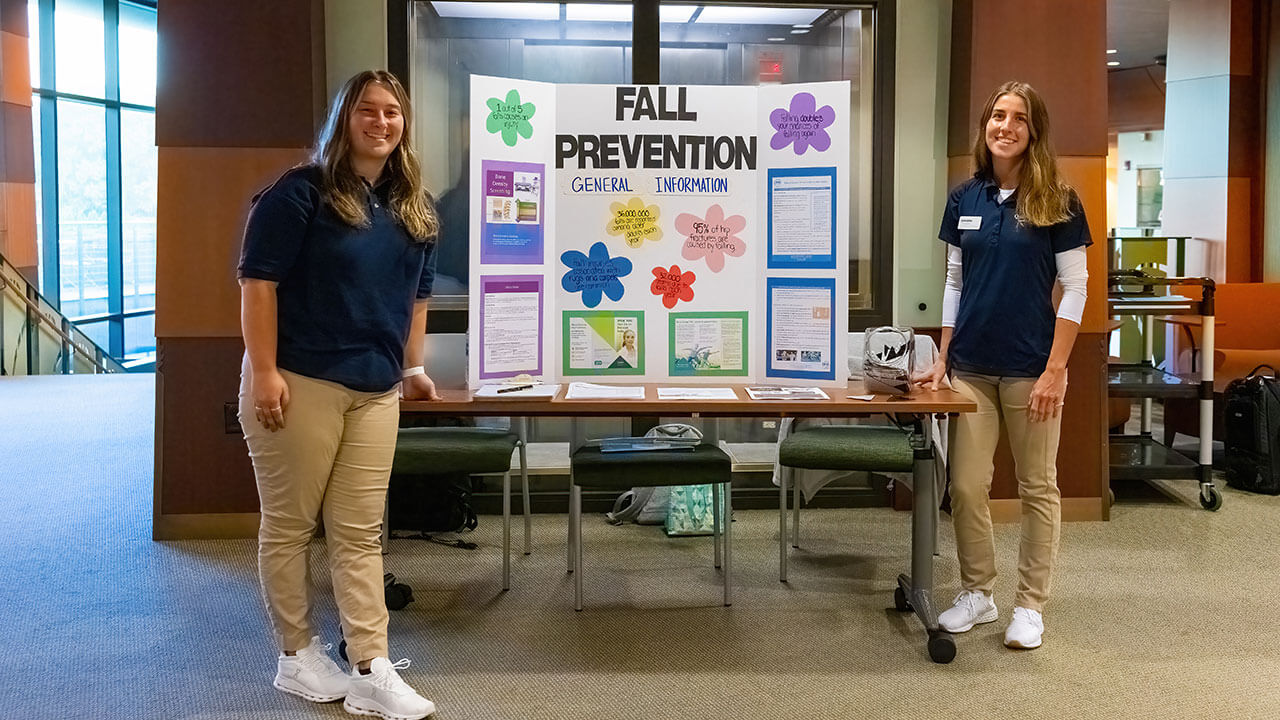 Two students stay by a general information poster regarding fall prevention