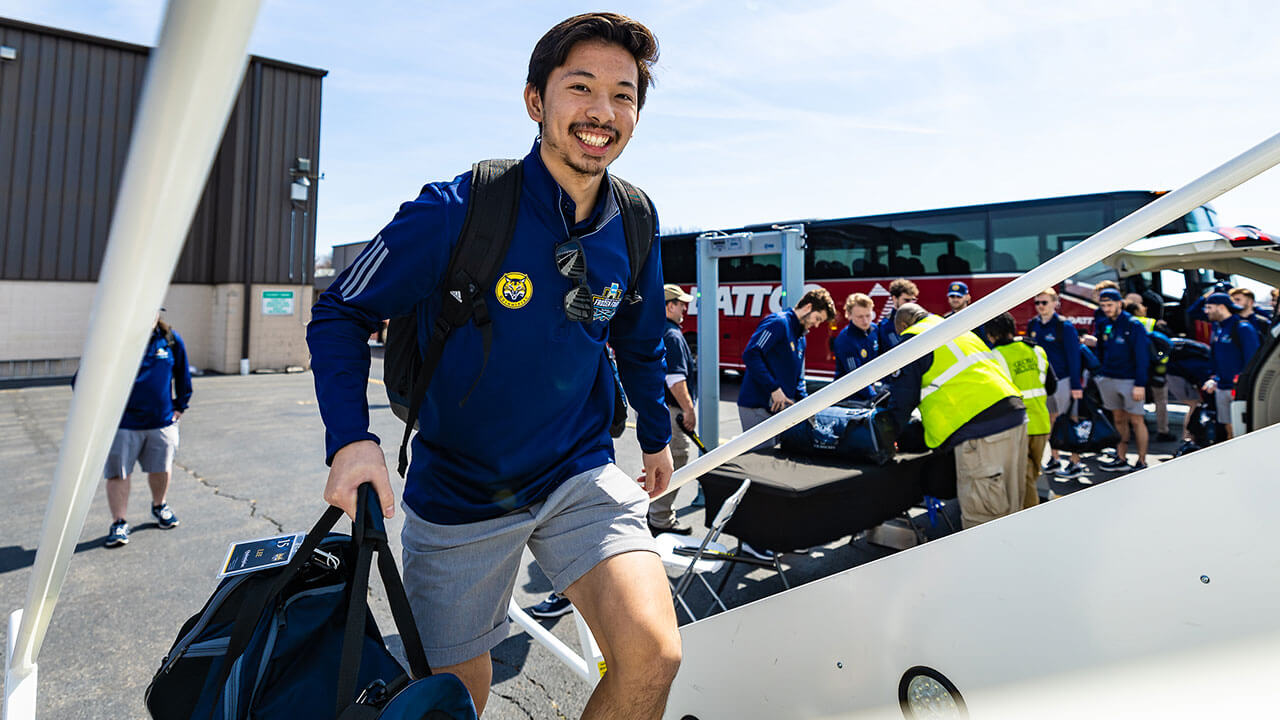 A member of the men's ice hockey team boards the plane to Tampa.