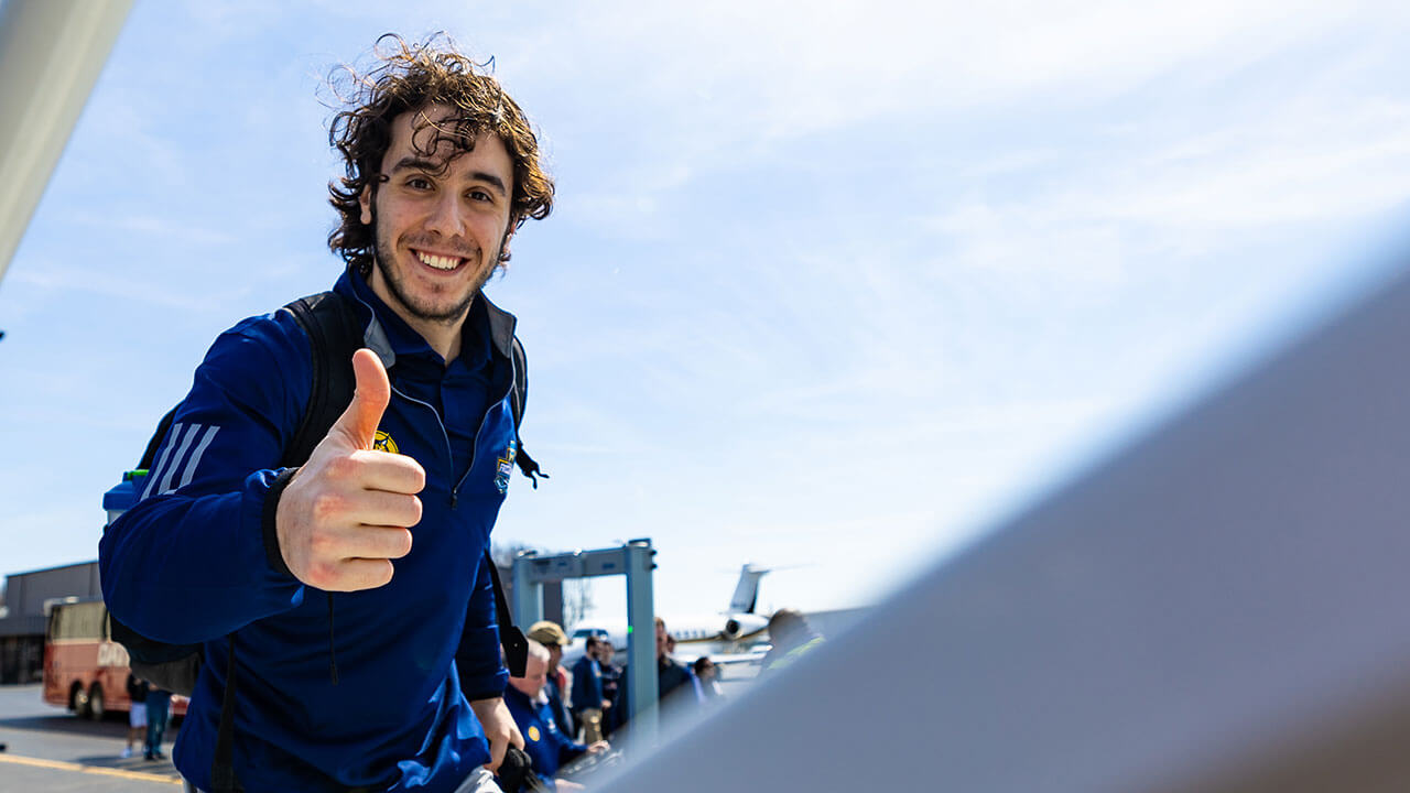 A men's ice hockey player gives a thumbs up.