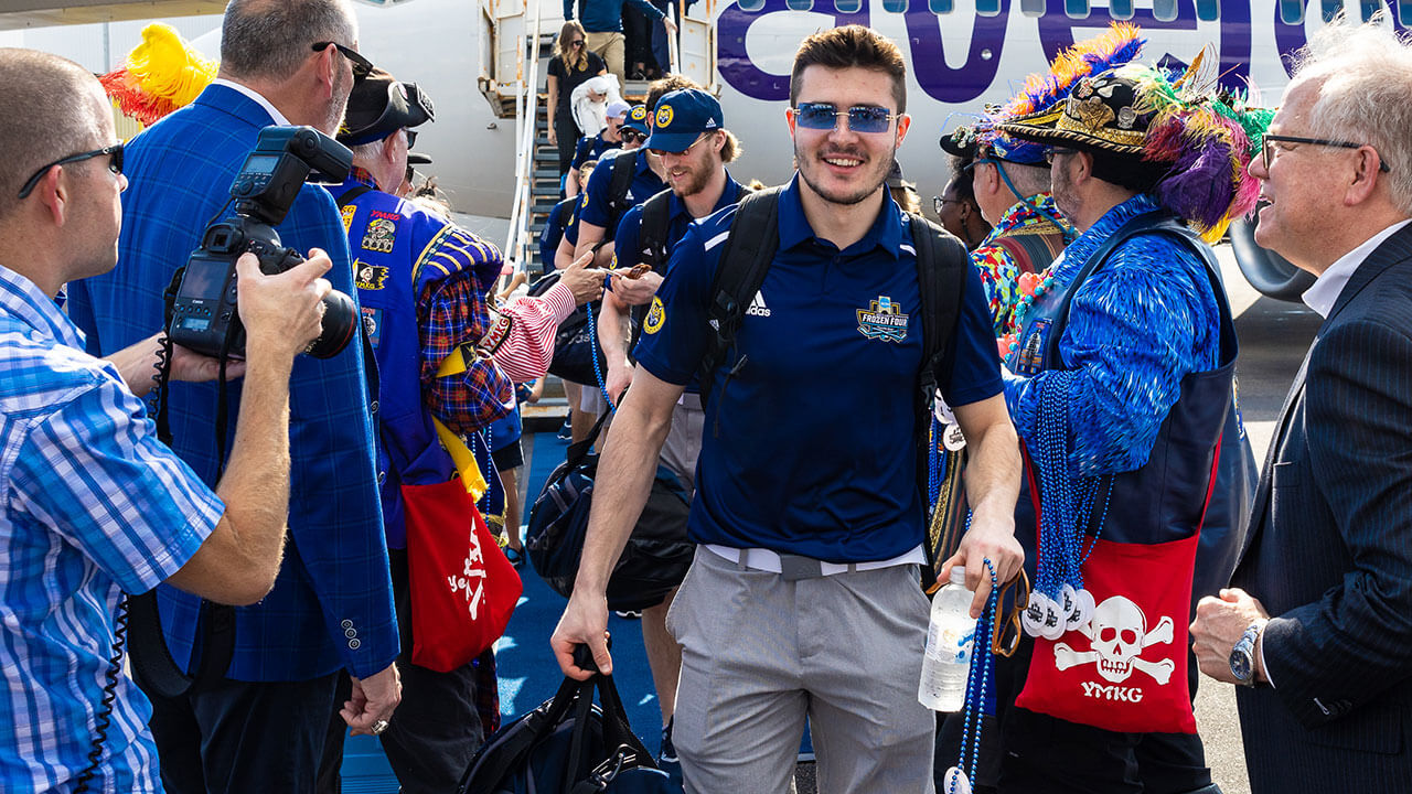 A men's ice hockey player is greeted by fans.