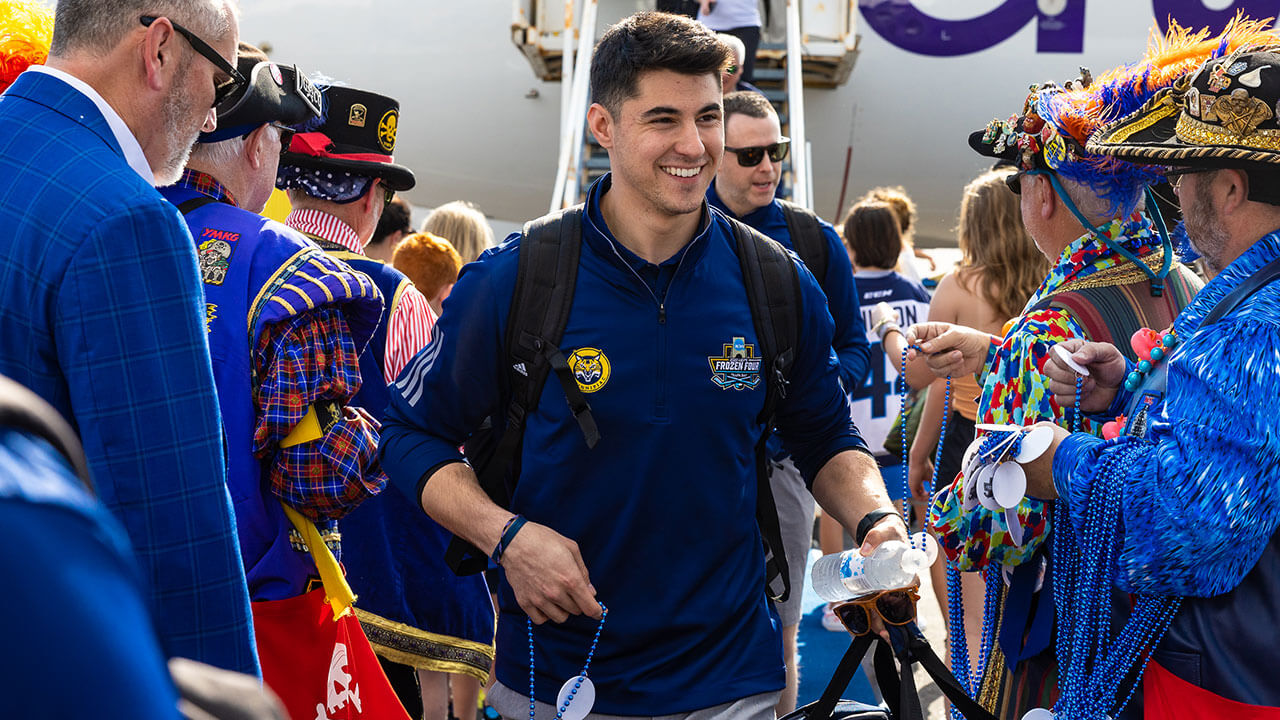 A men's ice hockey player is welcomed by fans.