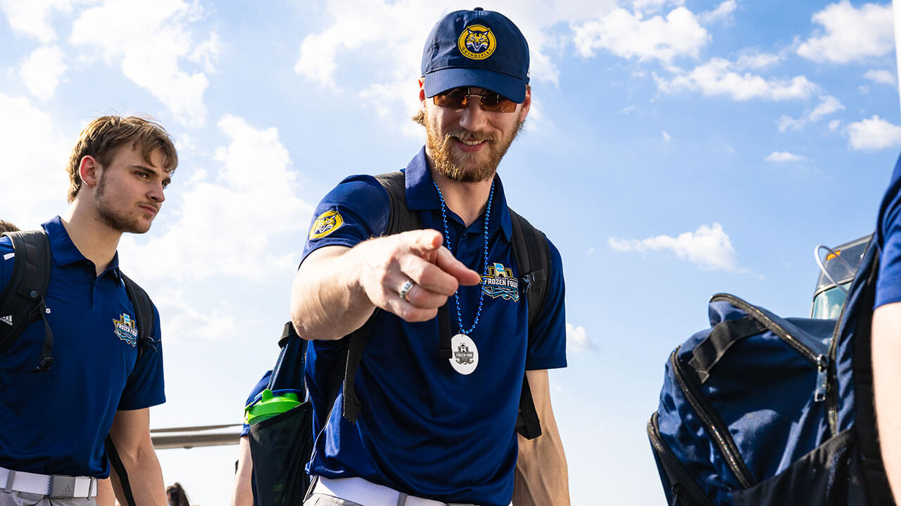 A member of the men's ice hockey team points to the camera.