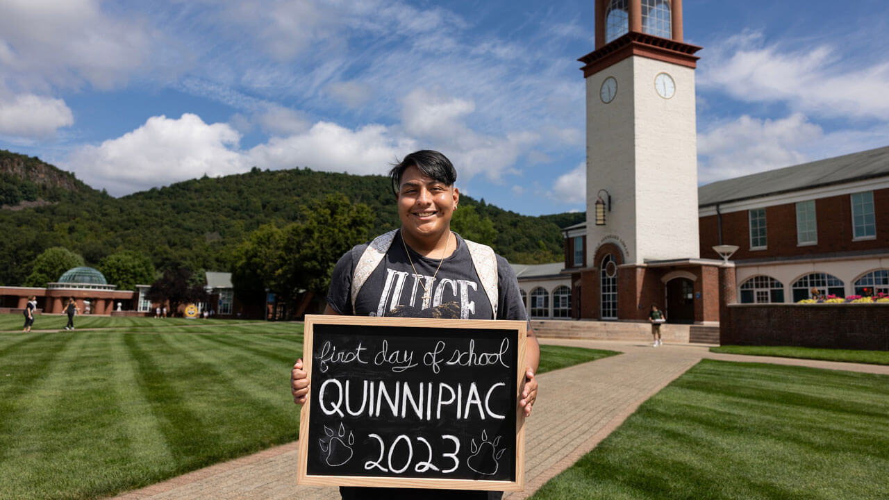 Student smiles for a photo on the first day of classes in front of the Arnold Bernard Library