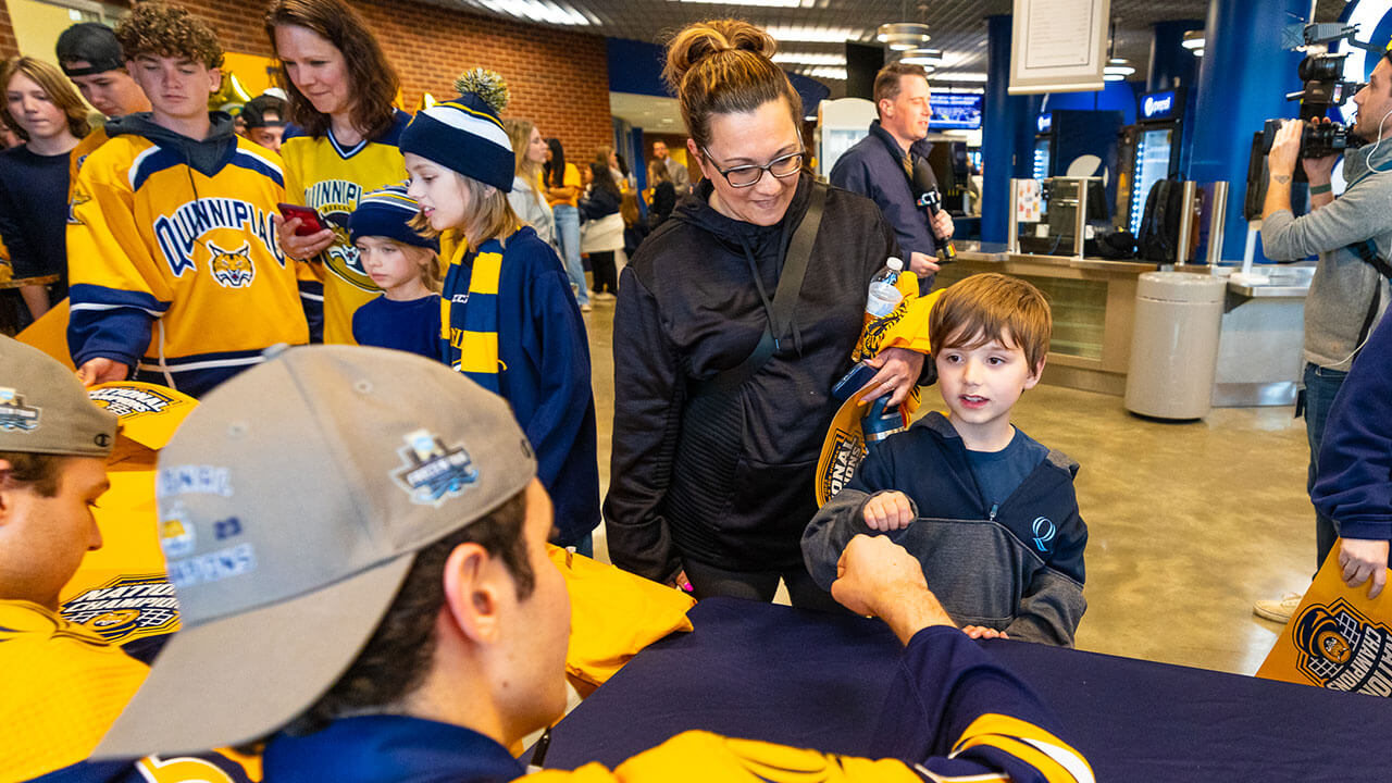 Quinnipiac mens ice hockey fan gives a player a fist pump