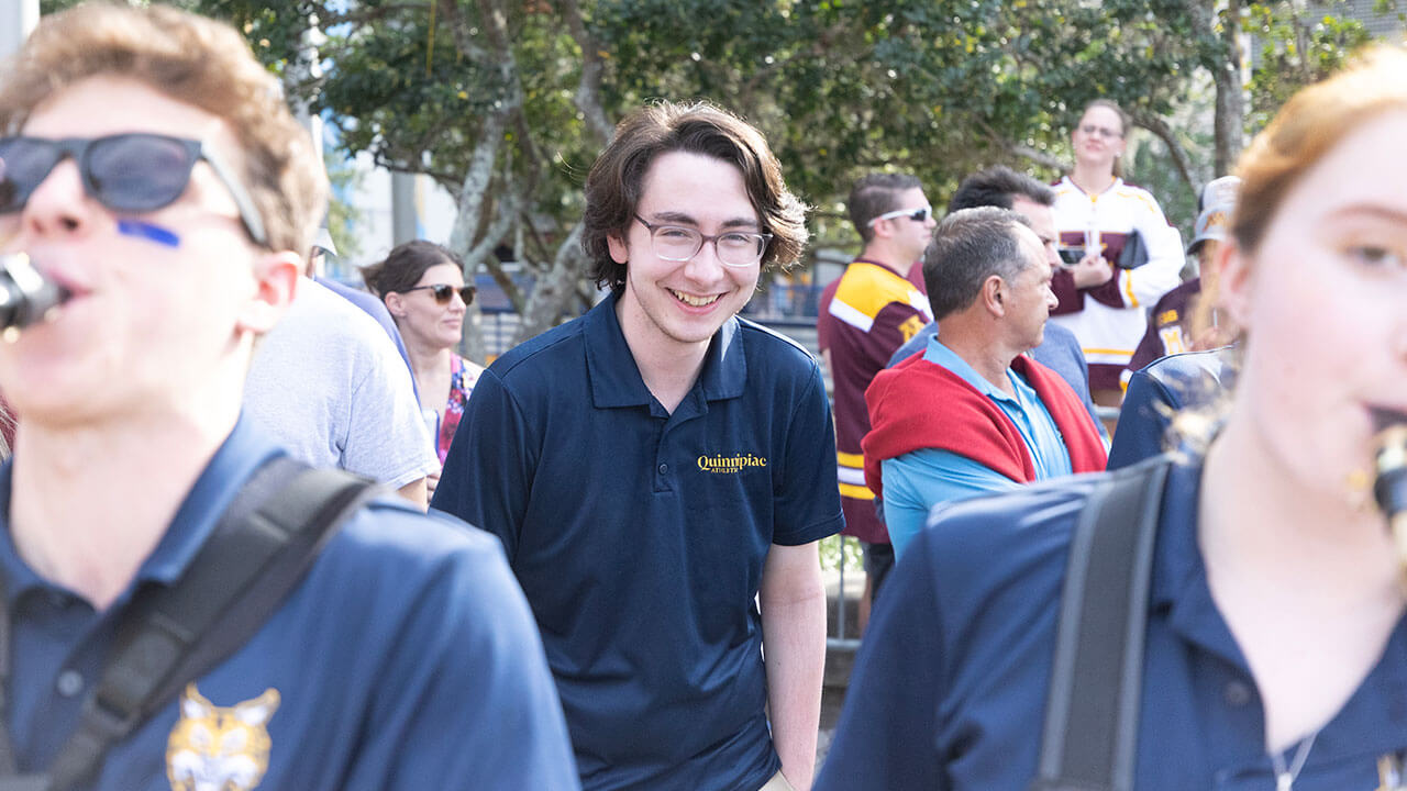 athletics employee grins behind two pep band members playing the saxophone