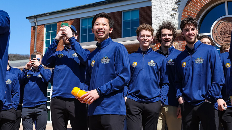 Members of the men's ice hockey team laugh as they launch tee shirts to the crowd