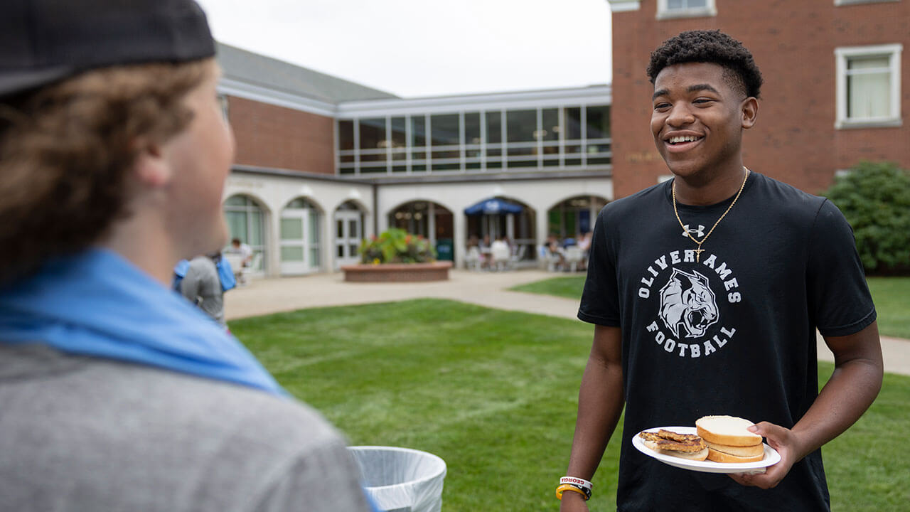 Students talking while enjoying burgers on their plates