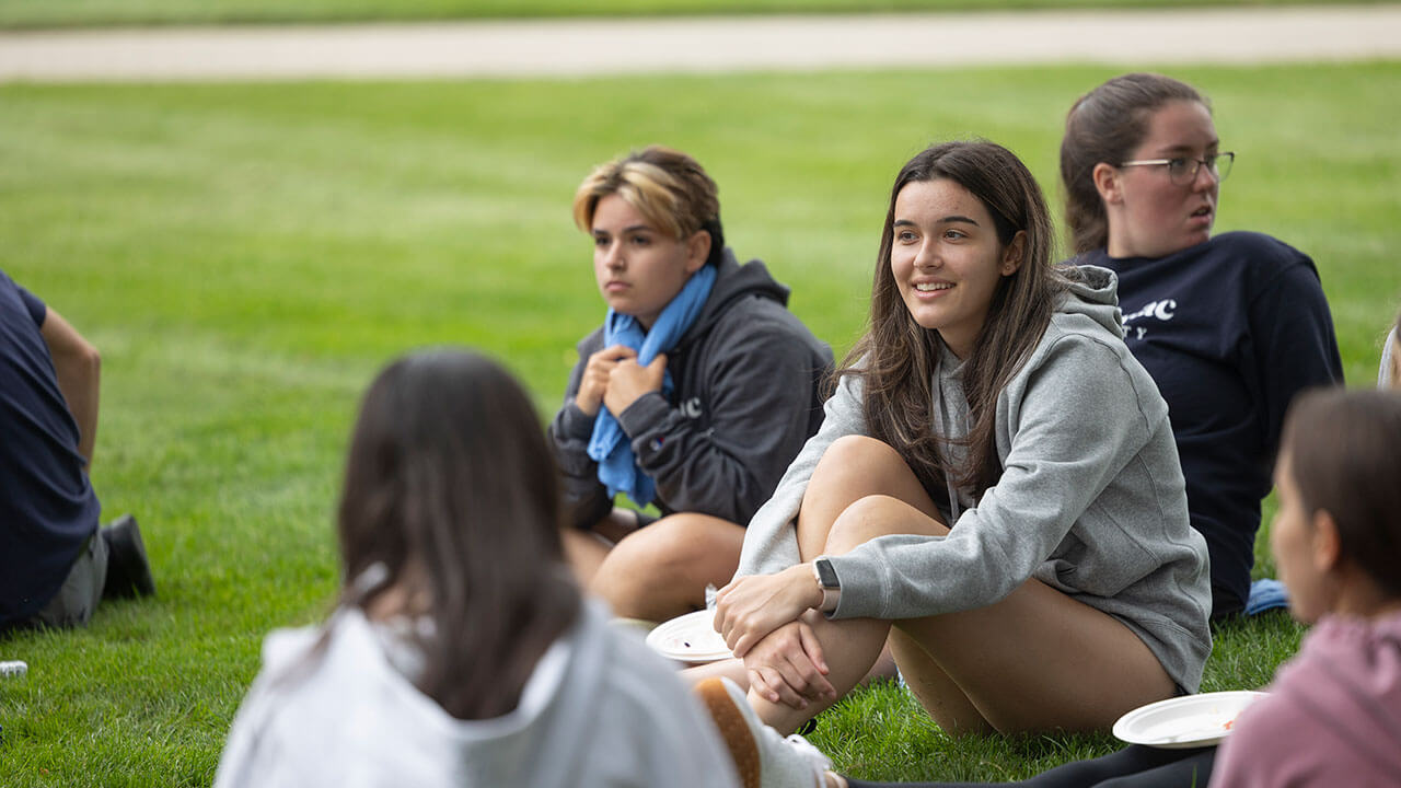 Girl in grey sweatshirt sitting on the grass smiling