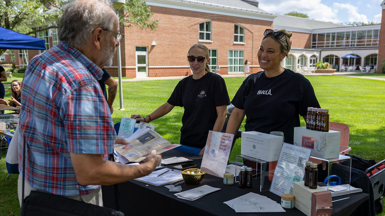 Local business owners smile while explaining their services to  a man