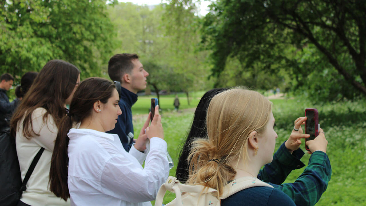 group of students hold up their phones to take pictures