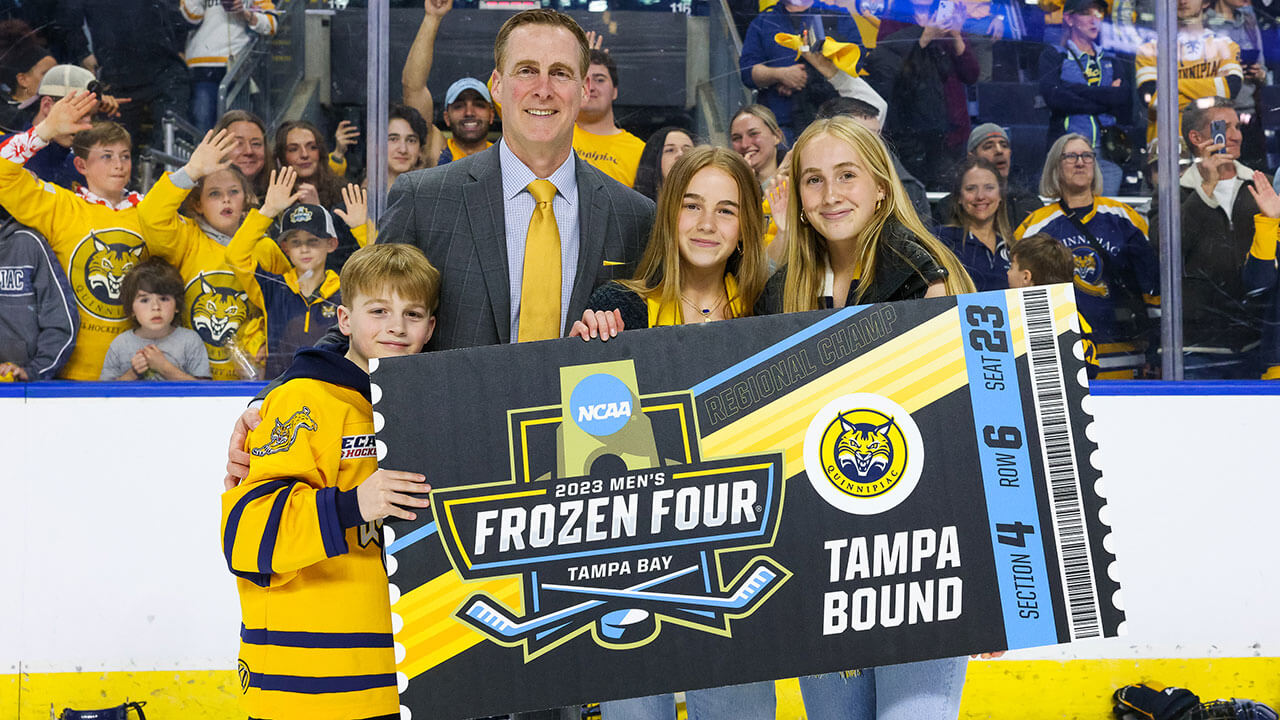 Rand Pecknold takes a picture with the Men's Ice Hockey team