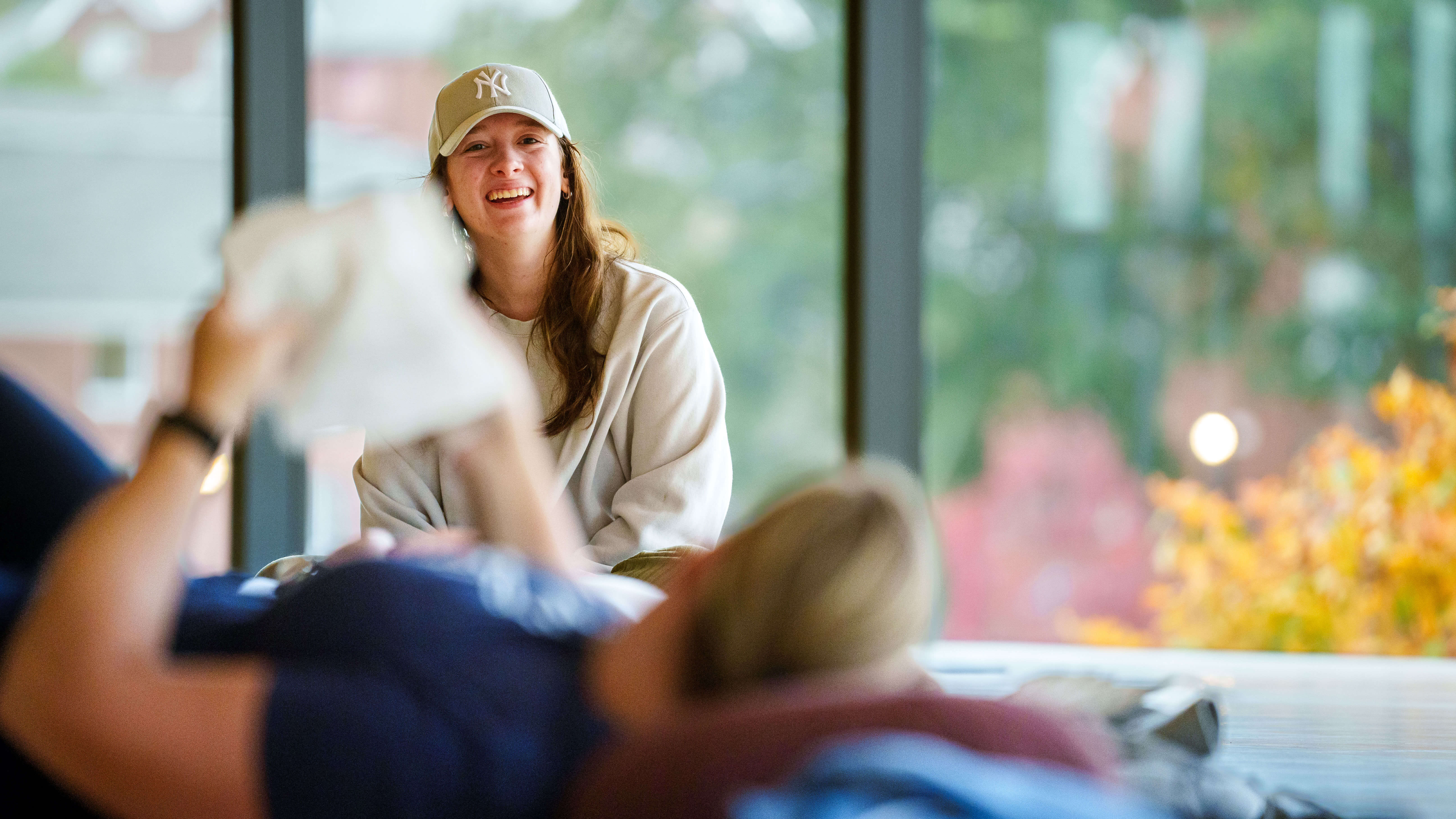 A young girl smiles wearing a Yankees tan hat in the rec center during the bobcat weekend mindfulness event.