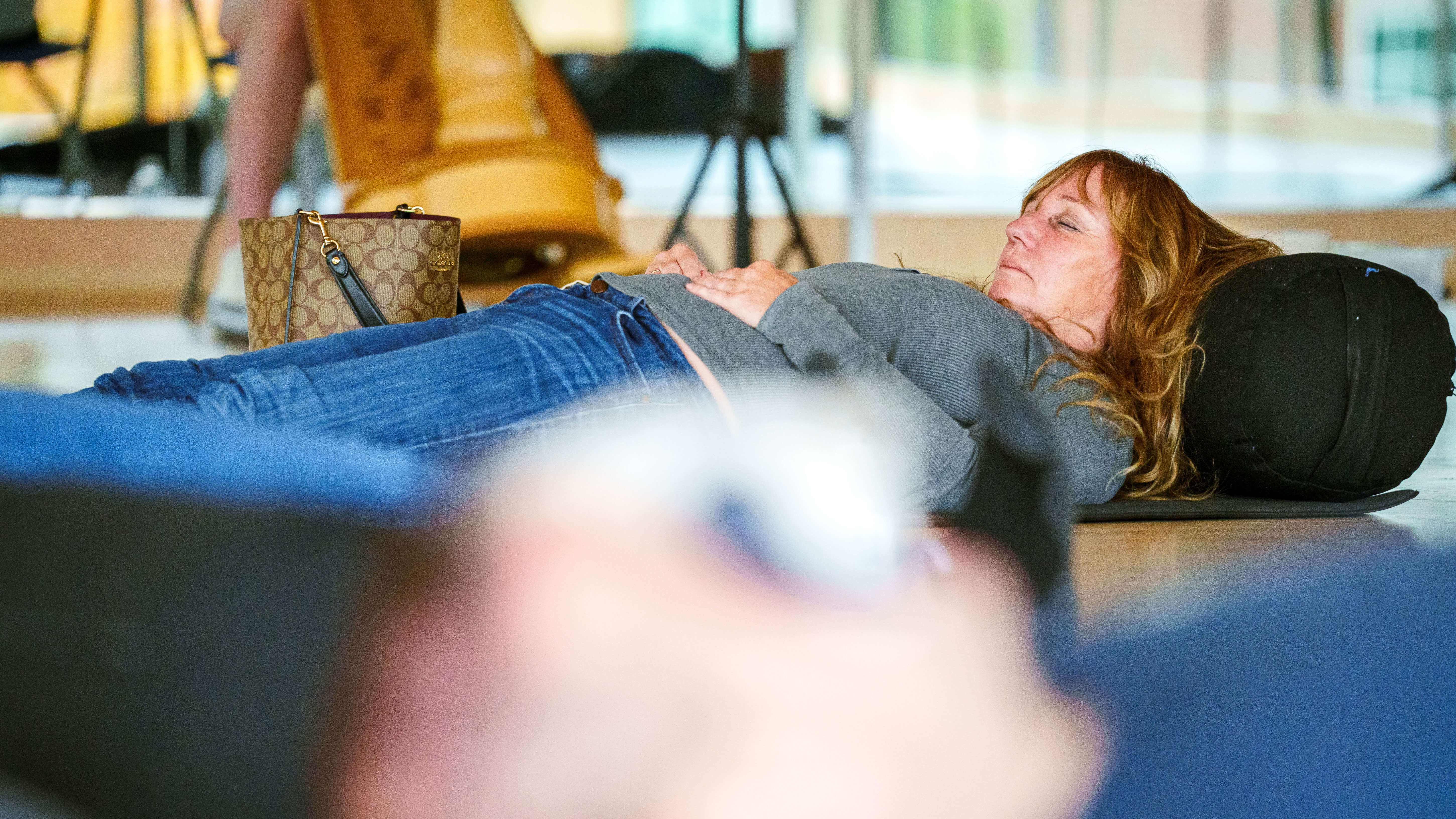 A woman lays her head on a piece of yoga equipment on the floor.