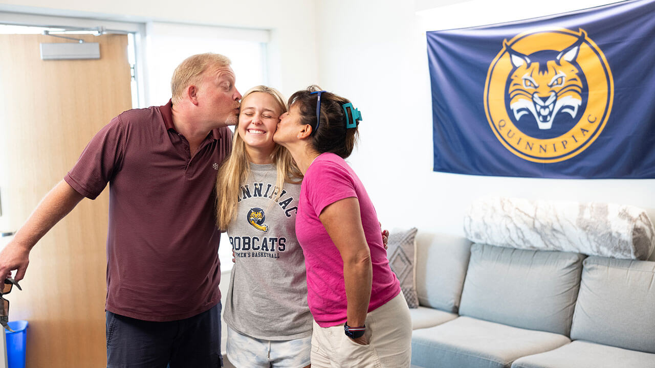 Parents kiss their child goodbye on the cheek