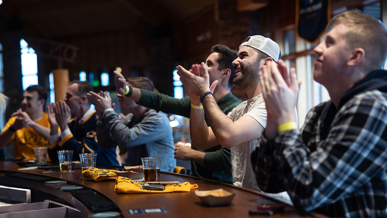 Students clap for the men's ice hockey team