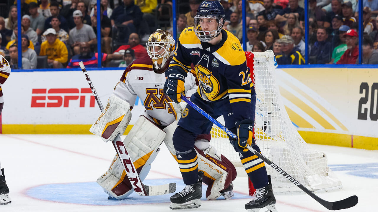 Quinnipiac ice hockey teammate waiting by Minnesota goal, blocking goalie