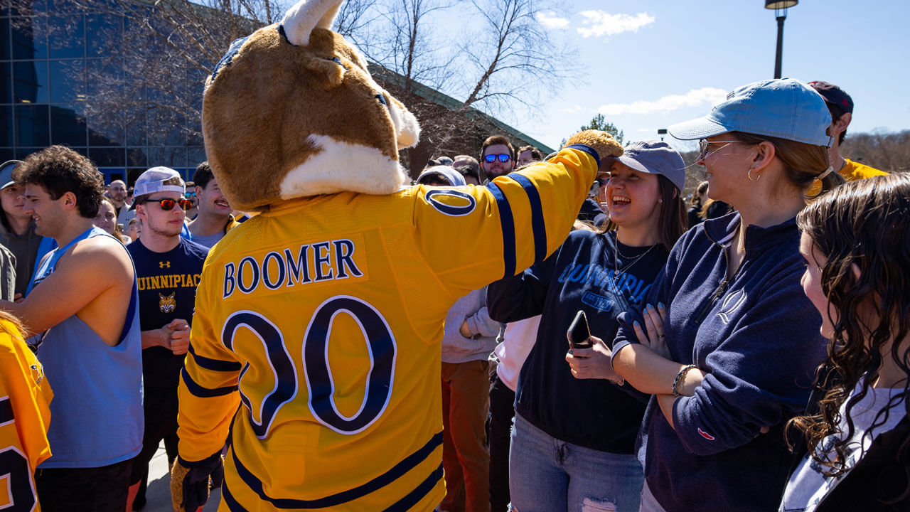 Boomer the bobcat high fiving fans awaiting hockey team's arrival