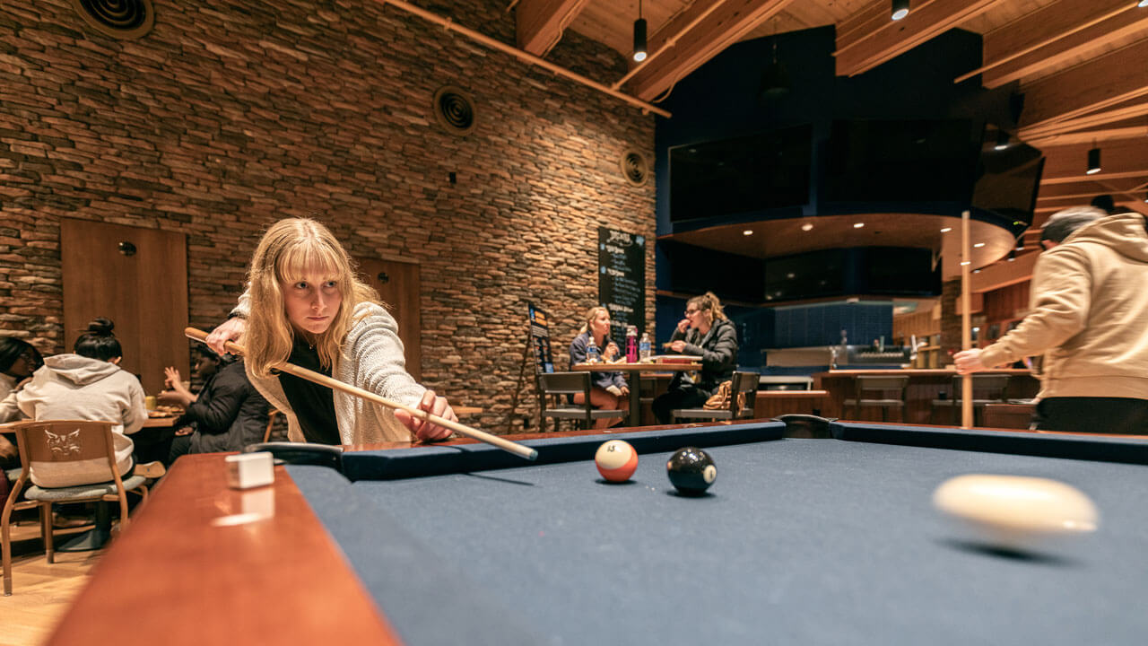 A student hits the cue ball in the pub