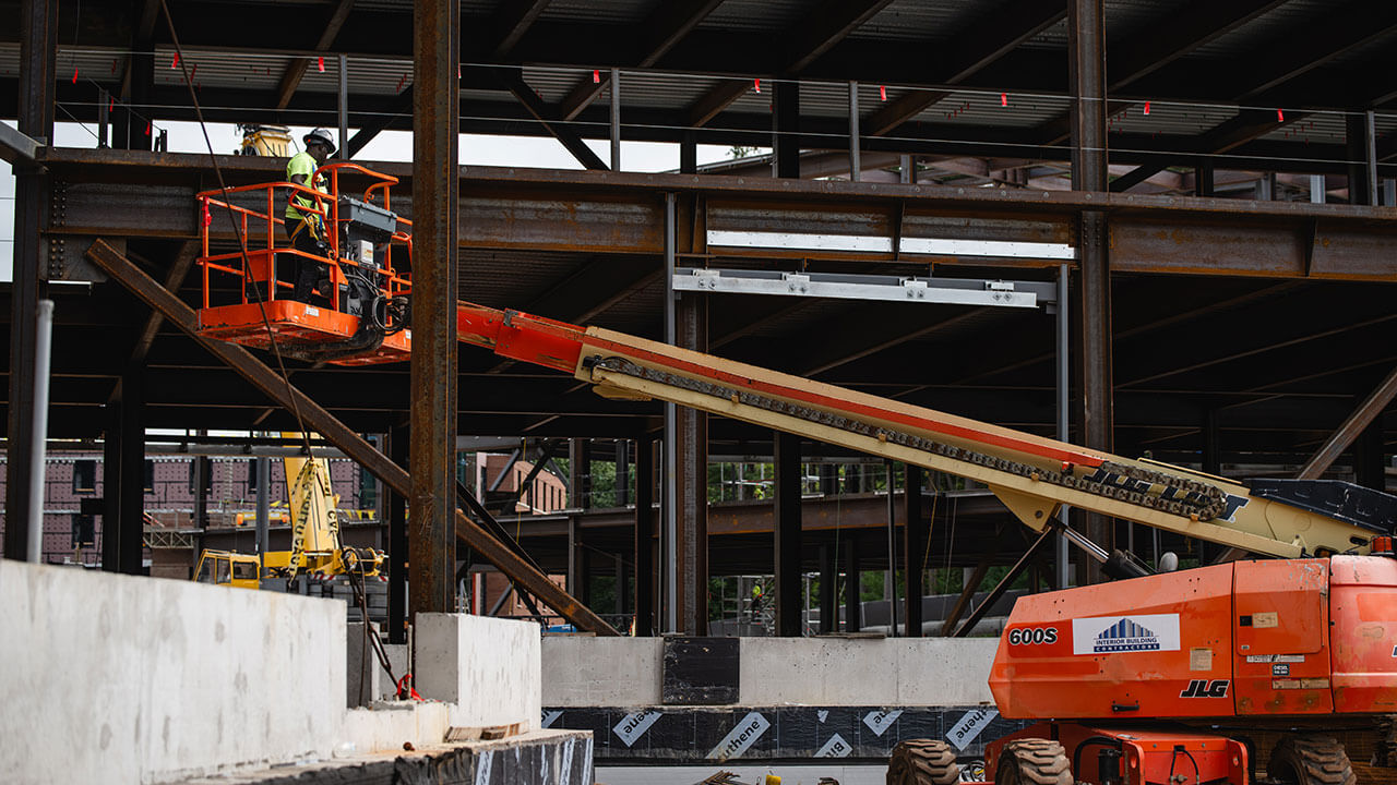 Orange construction lift in front of brown beams