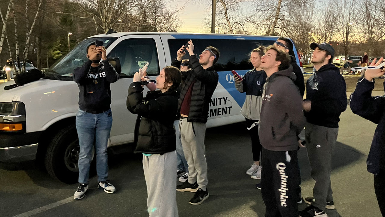 Students point their phones up to the sky.