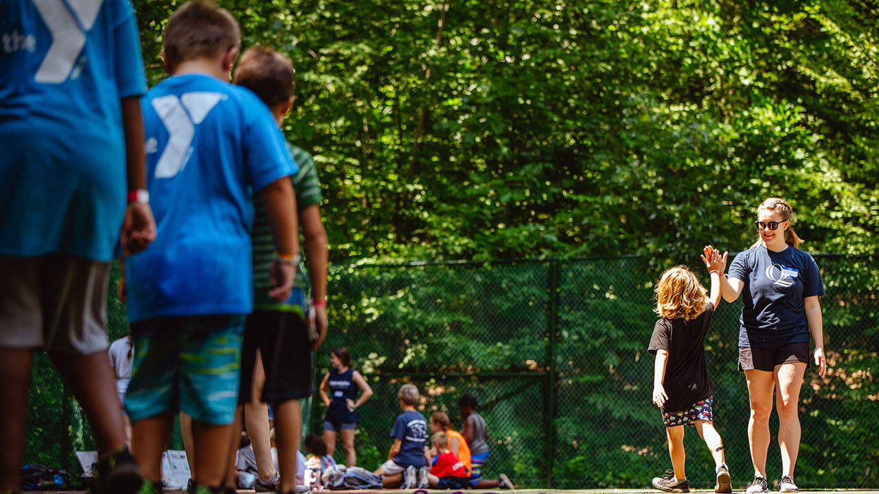 A student high fives a camper during a relay race