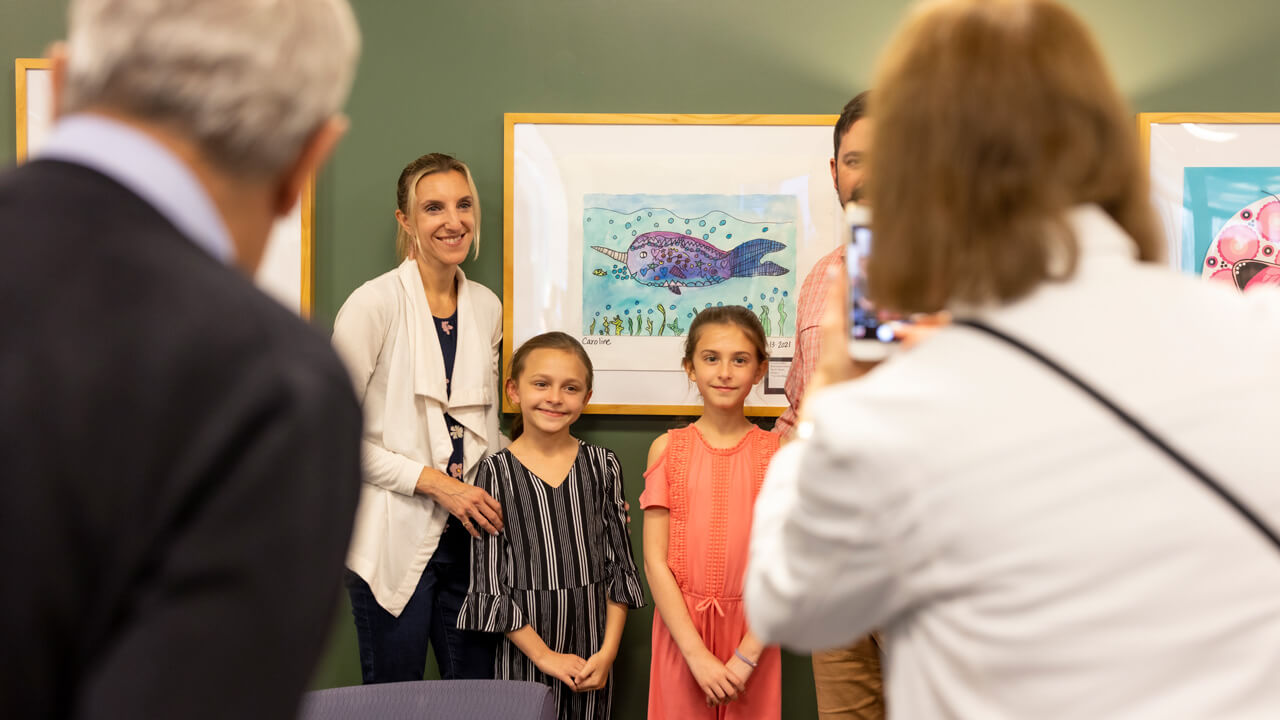 a family of 4 posing in front of art on a wall