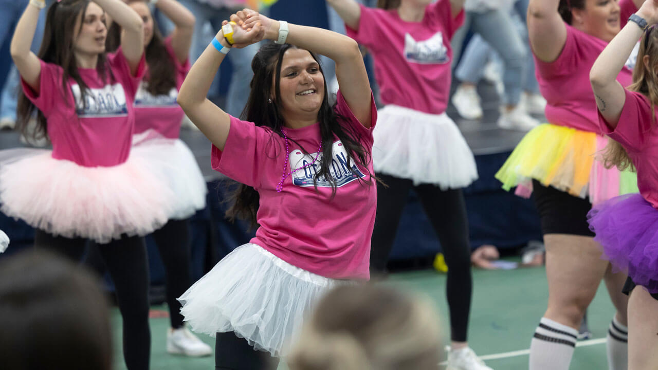 Group of girls wearing pink shirts and tutus dancing