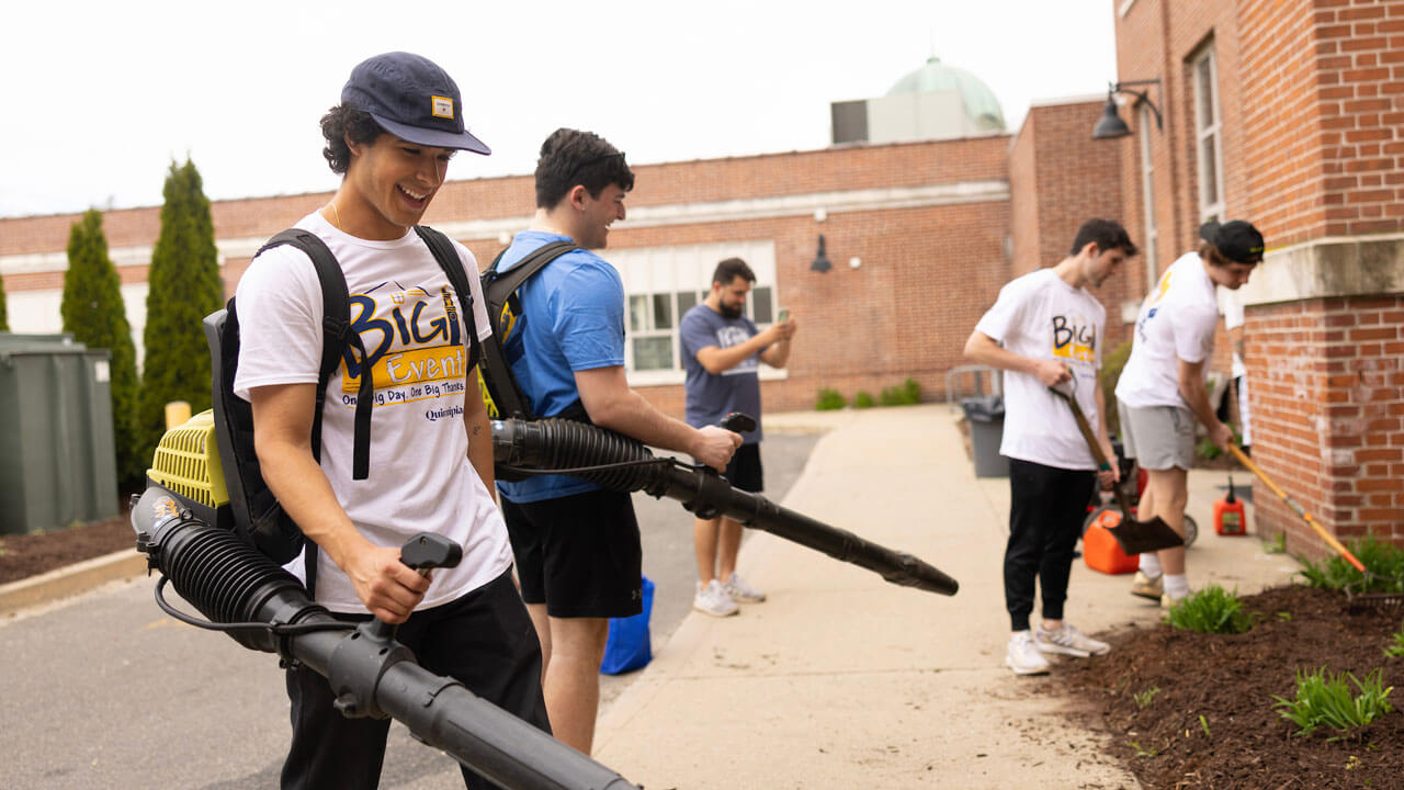 Boys leaf blowing a garden bed for the Big Event