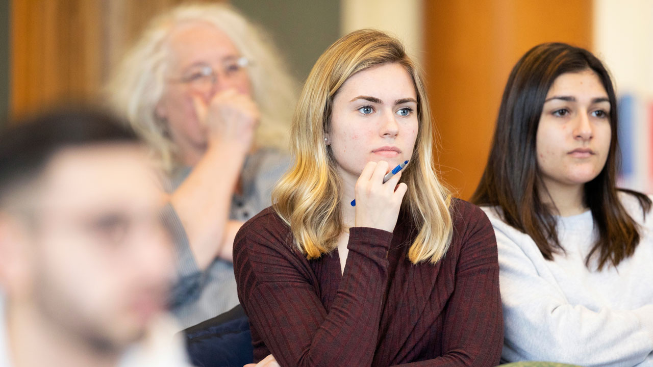 Students in an audience listen to presenters