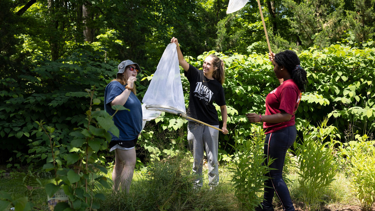 Two girls inspecting inside of insect net.